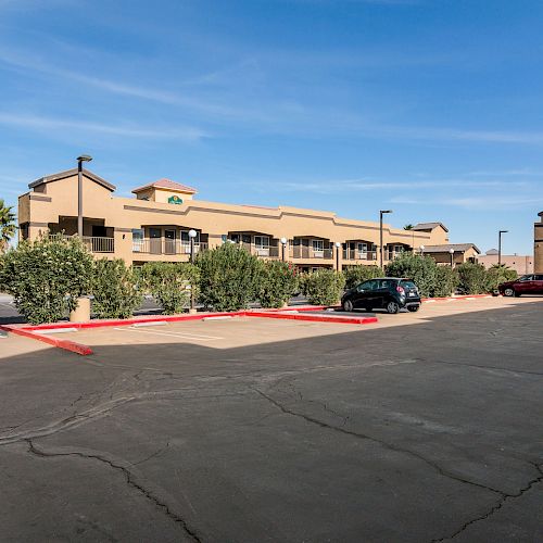 A parking lot in front of an Econo Lodge hotel with a few cars parked and a clear blue sky in the background.