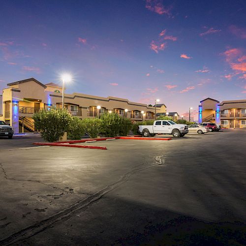 The image shows an Econo Lodge motel at dusk with a clear sky, parked vehicles, and illuminated exterior lights, creating a welcoming atmosphere.